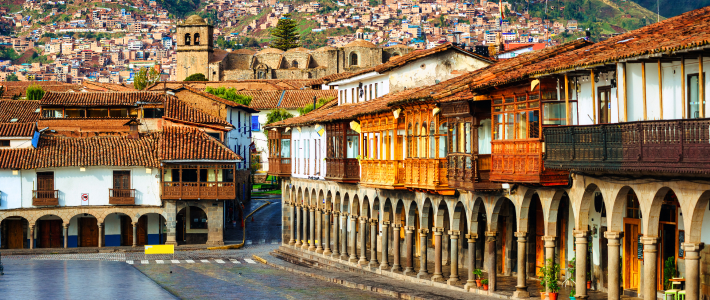 Vista del centro histórico de Cuzco con soportales coloniales, balcones de madera y la iglesia de la Compañía de Jesús al fondo, Perú