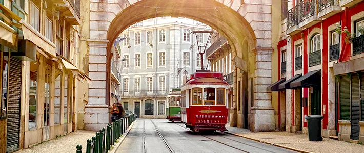 Tranvía histórico rojo circulando bajo el Arco de la Rua Augusta en el centro de Lisboa