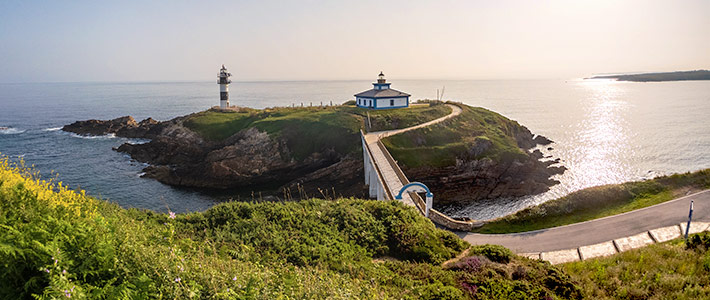 Faro de Illa Pancha en Ribadeo sobre pequeñas islas unidas por un puente con el mar cantábrico
