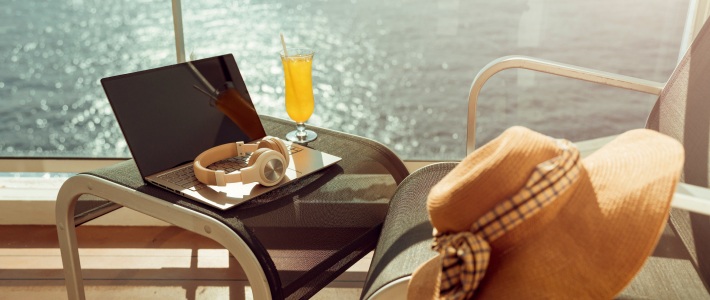 portátil y auriculares en crucero con vistas al mar y conexión a internet