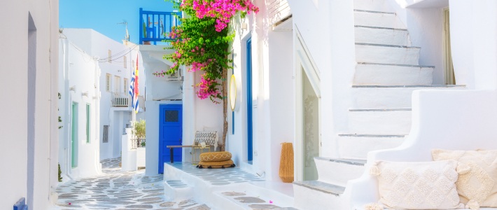 Calle blanca con puertas azules y buganvilla en Mykonos