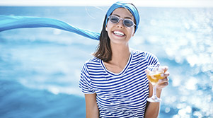 Chica sonriente con una copa en la cubierta de un crucero